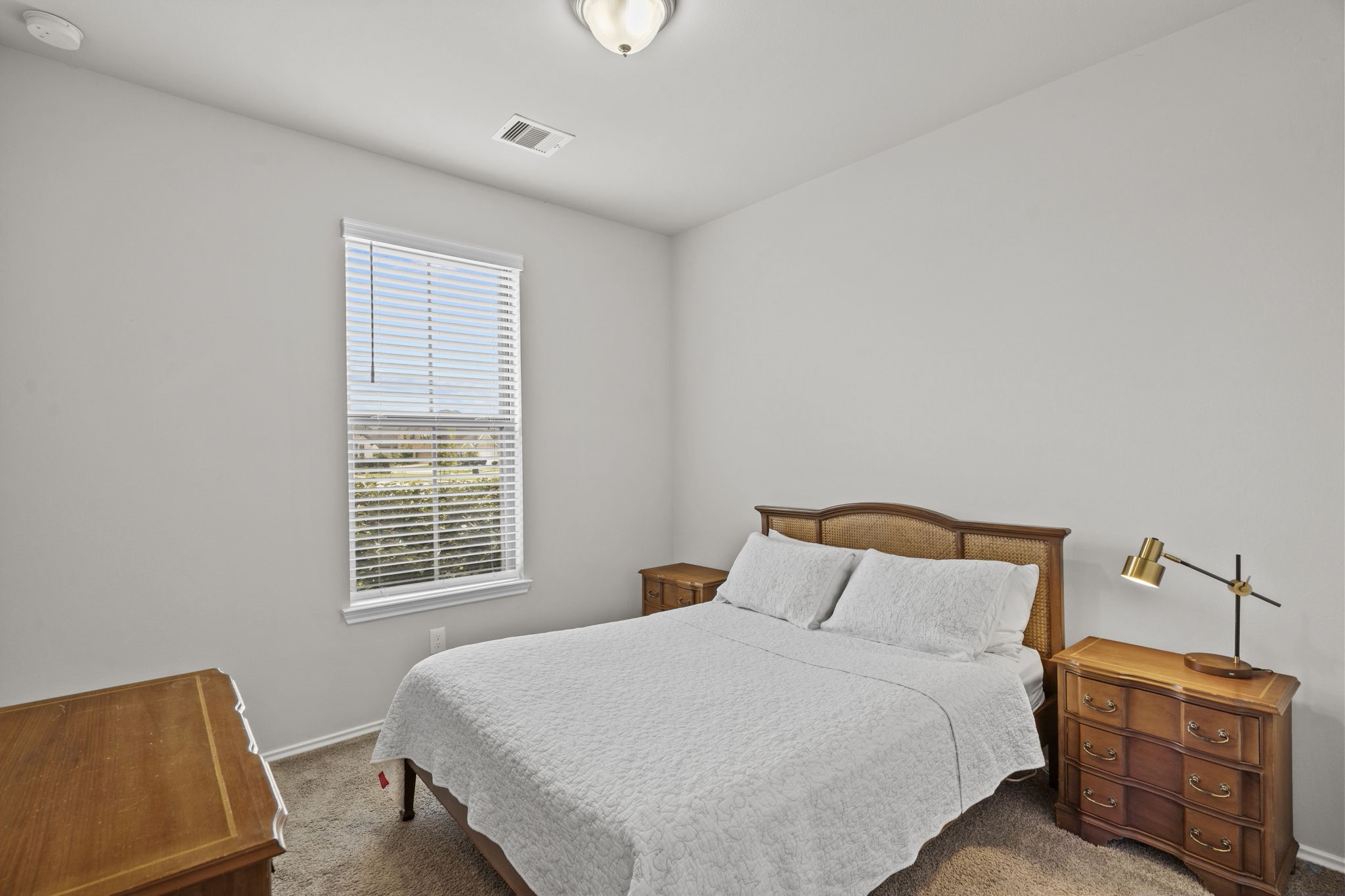 2011 Oak Leaf Court Manvel, TX 77578 - Photo 19 of 28 This cozy bedroom features a large window for natural light, neutral walls, and carpeted flooring. It includes a comfortable bed and matching wooden furniture, creating a warm and inviting atmosphere.