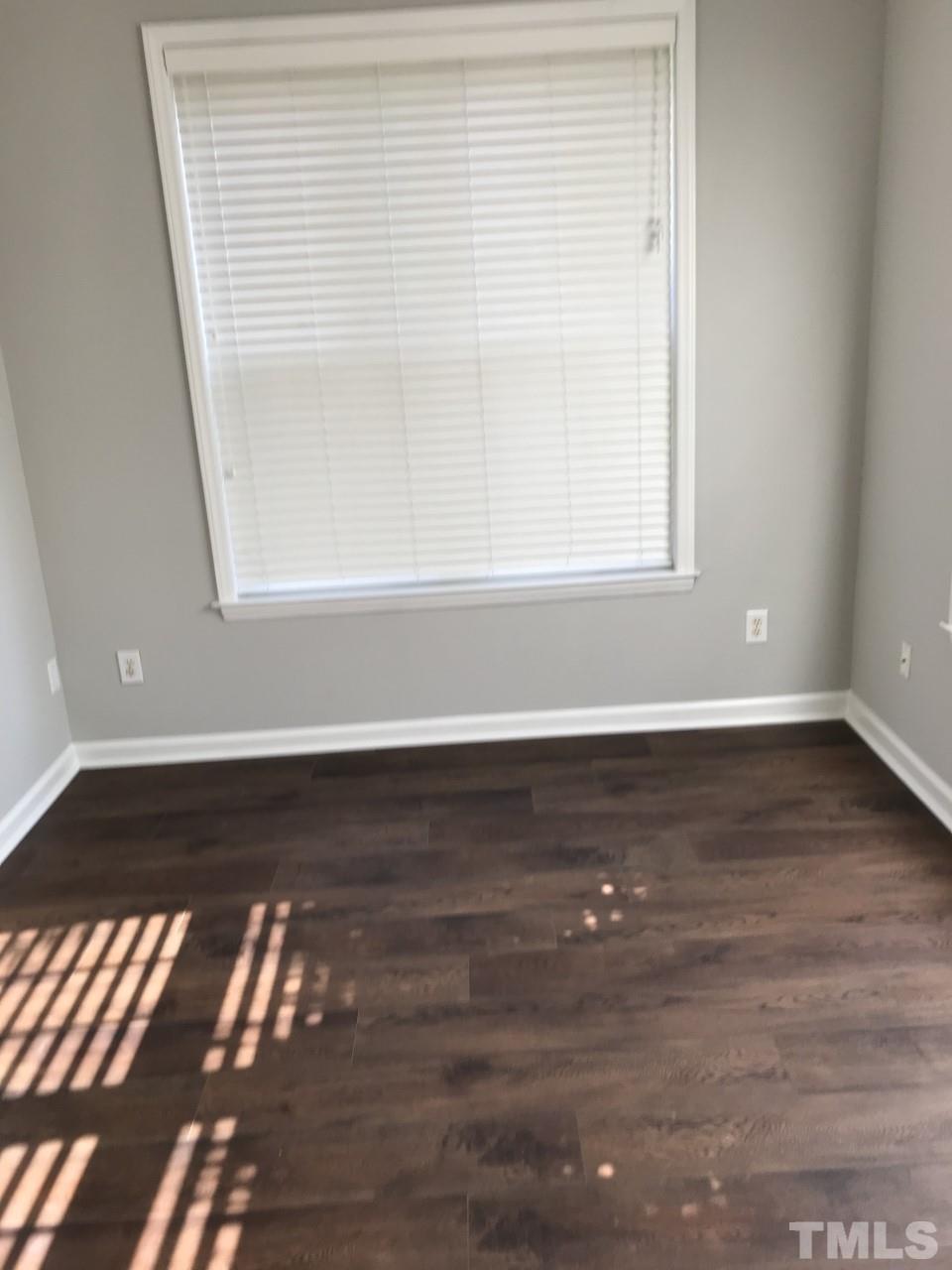 1701 Tiffany Bay Court, Unit 102 Raleigh, NC 27609 - Photo 13 of 13 a view of an empty room with wooden floor and a window
