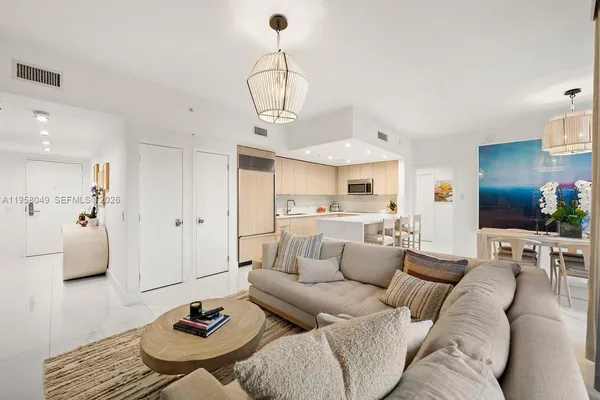 a living room with furniture kitchen view and a chandelier
