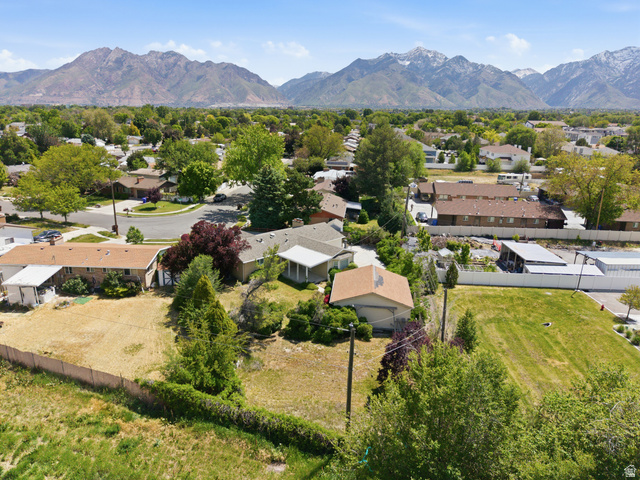 148 Tennyson Avenue Sandy, UT 84070 - Photo 51 of 55 Expansive property with a large undeveloped lot, established trees and shrubs, and a distinct brown-roofed outbuilding