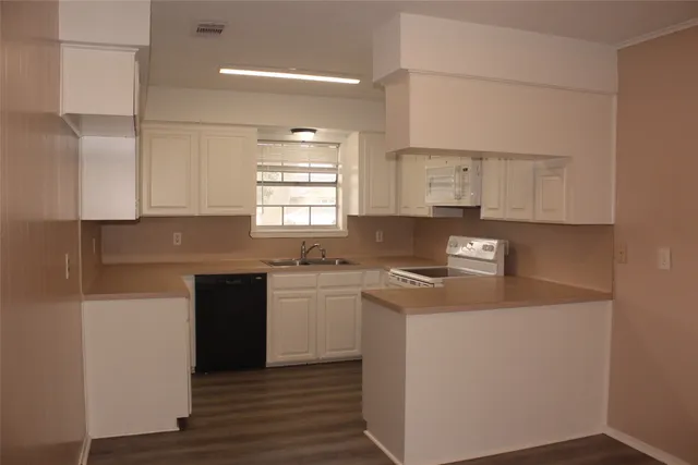 an empty room with wooden floor cabinet and windows