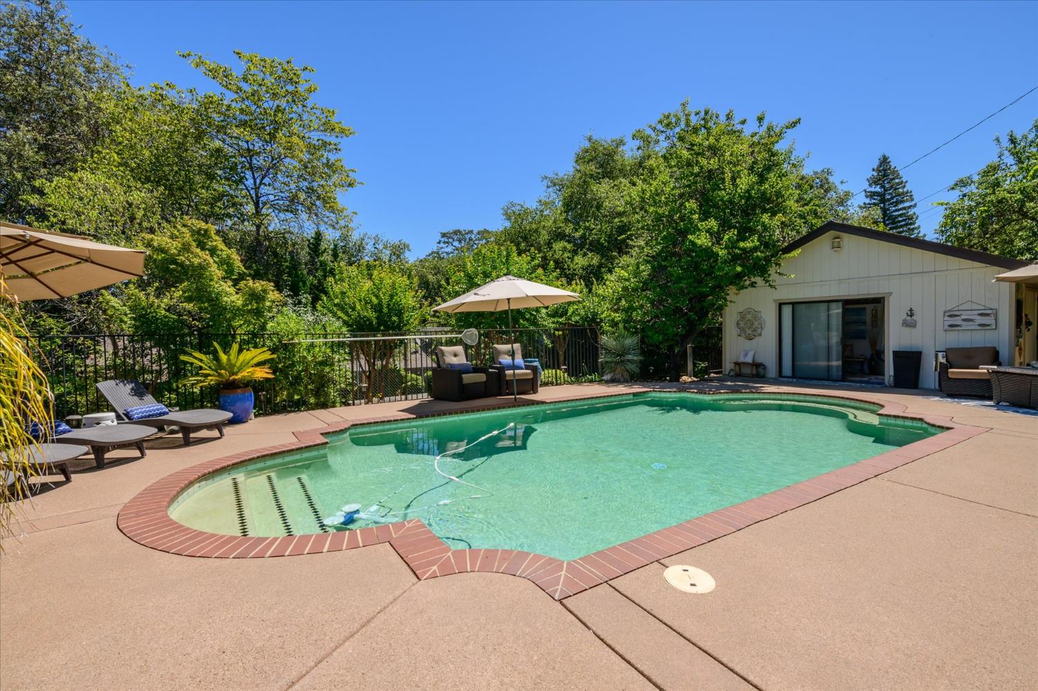 3165 Oakwood Road Cameron Park, CA 95682 - Photo 44 of 55 The pool is the perfect spot to enjoy these warm days—spacious and inviting, complete with a pool house and convenient half bath for changing and freshening up. Whether you’re grabbing refreshments, relaxing in the sun, or entertaining guests, this outdoor space is designed for effortless enjoyment and easy living.