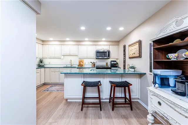 a kitchen with stainless steel appliances granite countertop a table chairs refrigerator and sink