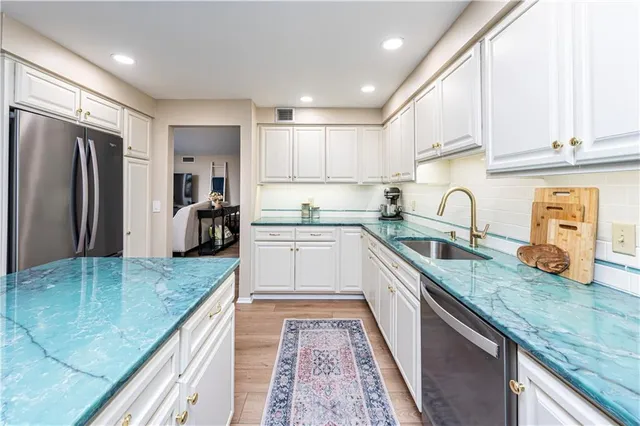 a kitchen with granite countertop a sink a counter top space stainless steel appliances and cabinets