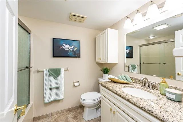 a bathroom with a granite countertop toilet a sink and a mirror