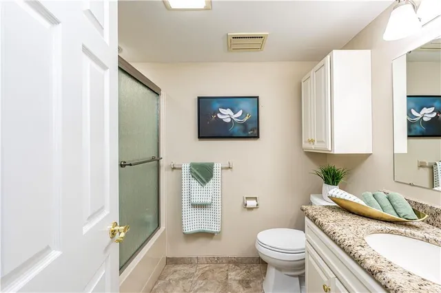 a bathroom with a granite countertop toilet sink and mirror