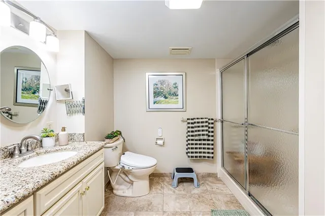 a bathroom with a granite countertop toilet a sink and a mirror