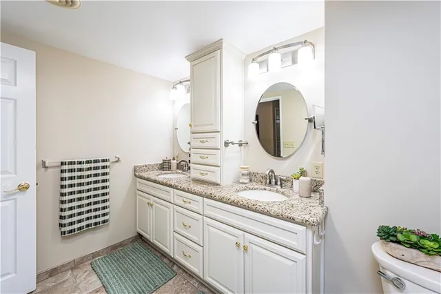a bathroom with a granite countertop double vanity sink and a mirror