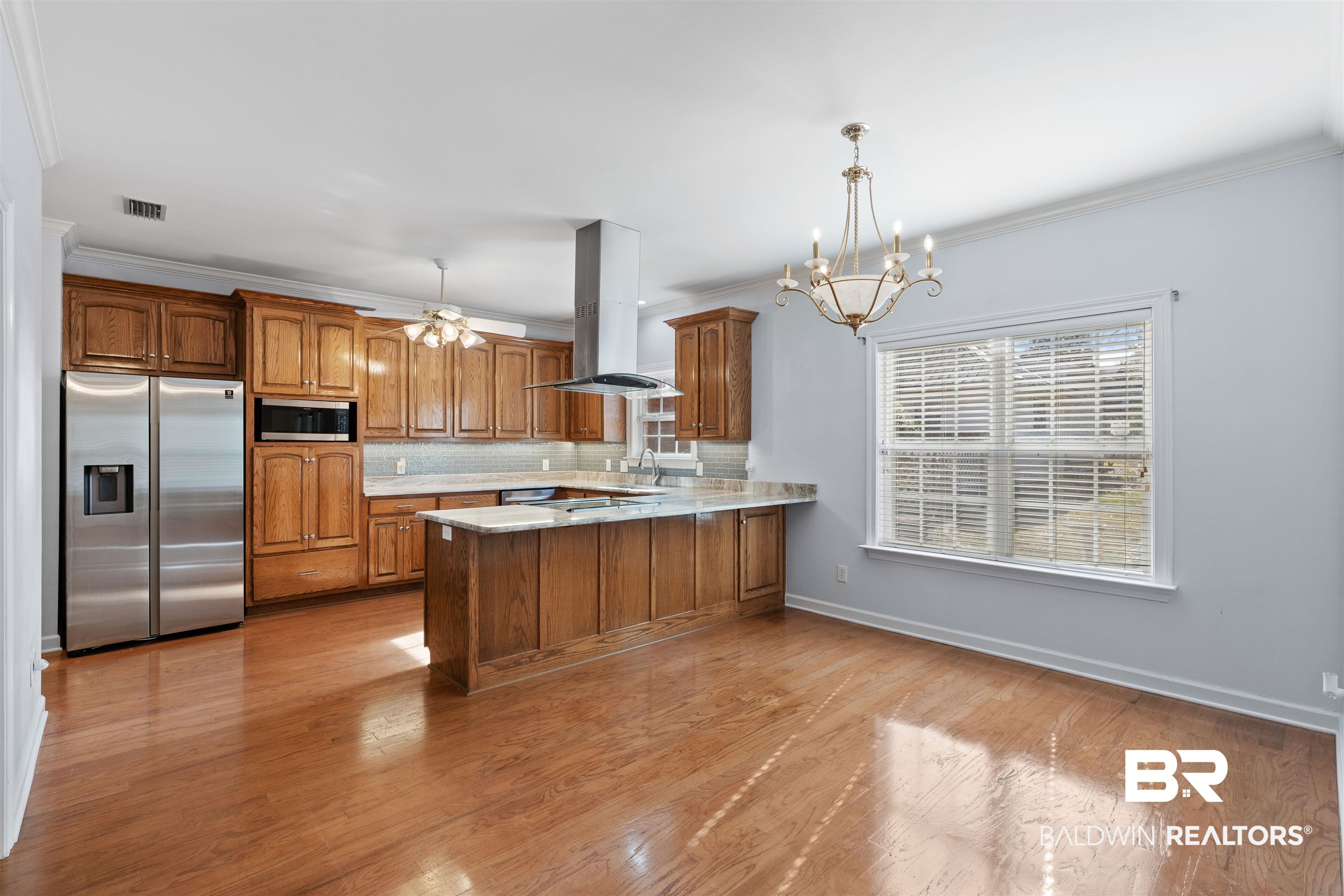 4 Judd Trail Daphne, AL 36527 - Photo 13 of 45 Kitchen with decorative backsplash, appliances with stainless steel finishes, island exhaust hood, a peninsula, and brown cabinetry