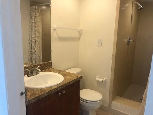 a bathroom with a granite countertop sink toilet and shower