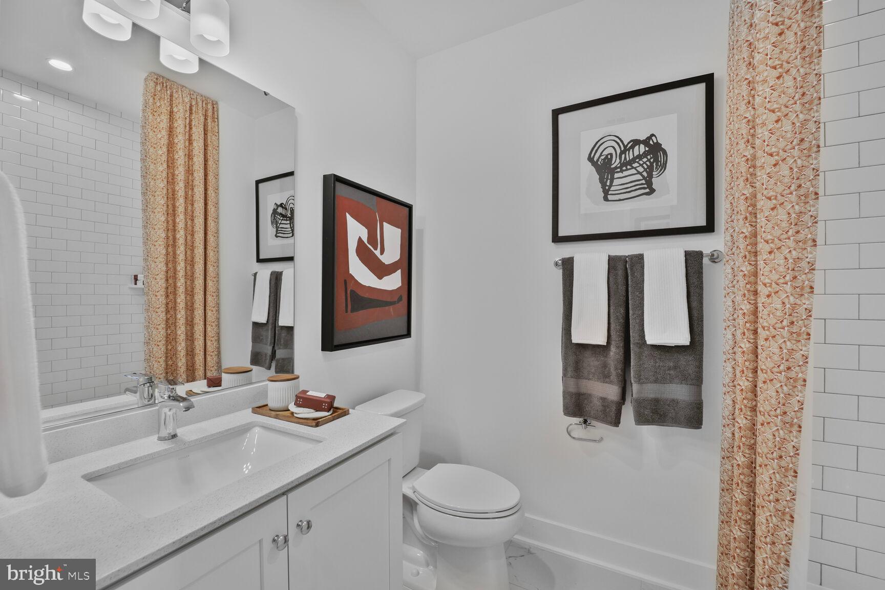 61 Lower Service Road Northwest, Unit ATWOOD 884 Washington, DC 20422 - Photo 13 of 21 a bathroom with a toilet sink and mirror