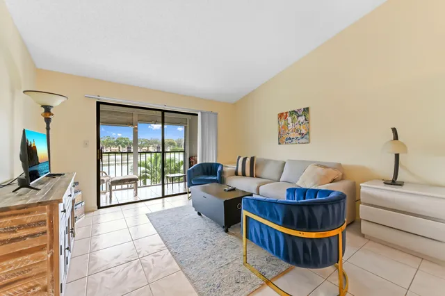 a living room with furniture a flat screen tv and a floor to ceiling window