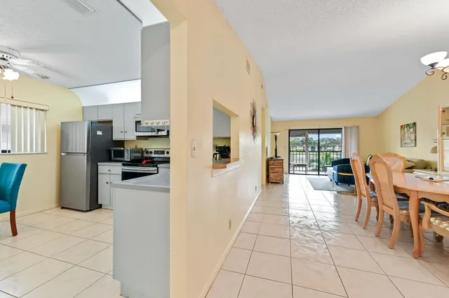 a large white kitchen with cabinets a refrigerator a stove a sink dishwasher and a dining table with wooden floor