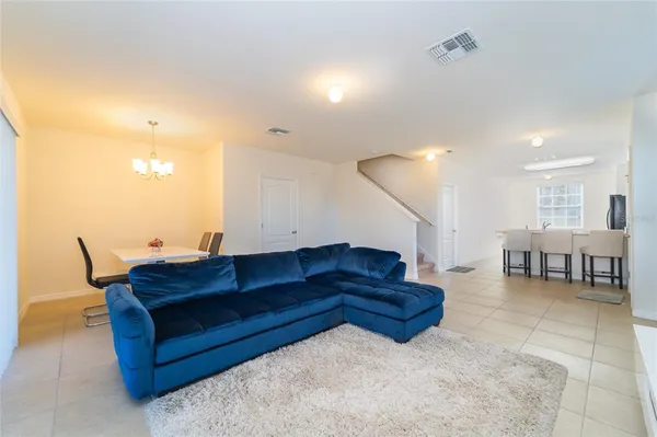 a living room with couches and kitchen view with wooden floor