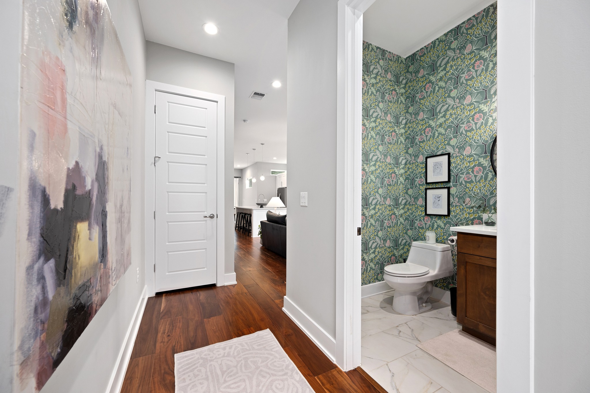 1103 Saucedo Street, Unit 1 Austin, TX 78721 - Photo 5 of 40 Enter into a hallway featuring rich hardwood floors and recessed lighting, leading to a charming bathroom.