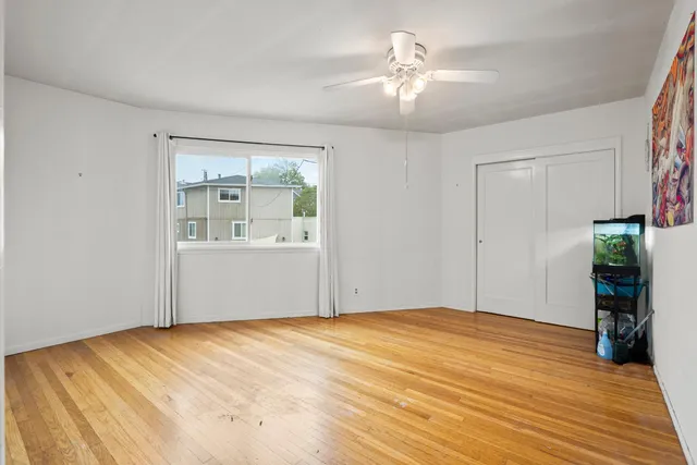 a view of empty room with wooden floor and fan