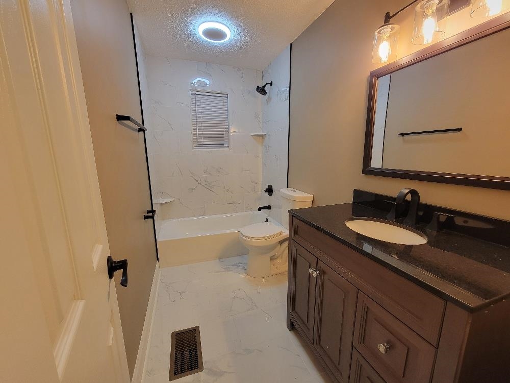 913 Chambliss Road Memphis, TN 38116 - Photo 12 of 16 Contemporary bathroom featuring a dark wood-finish vanity with a dark countertop, an oval undermount sink, and a framed mirror