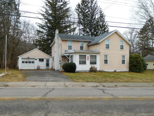 a view of a house with a yard and large tree