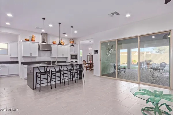 a dining hall with stainless steel appliances granite countertop a table and chairs
