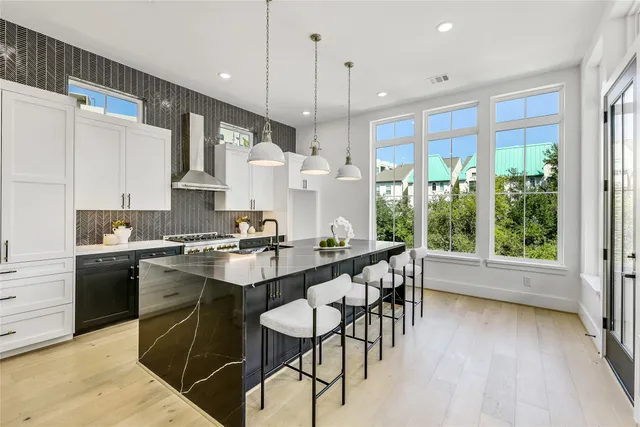 a kitchen with stainless steel appliances granite countertop a stove a sink dishwasher a refrigerator and white cabinets with wooden floor