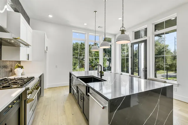 a kitchen with granite countertop a stove a sink a refrigerator and wooden floor