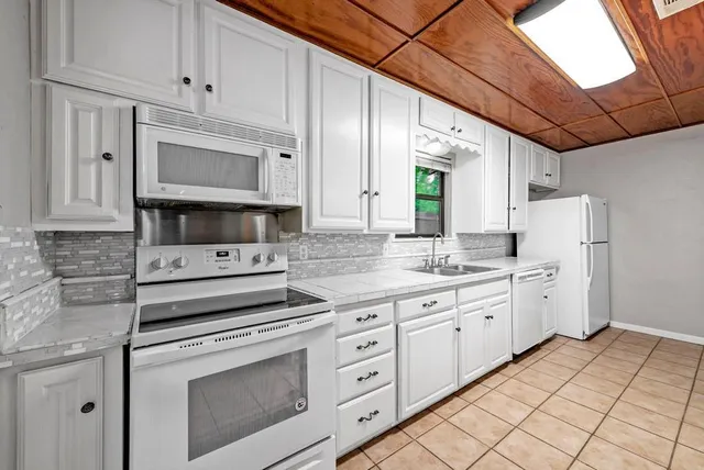 a kitchen with white cabinets and white appliances