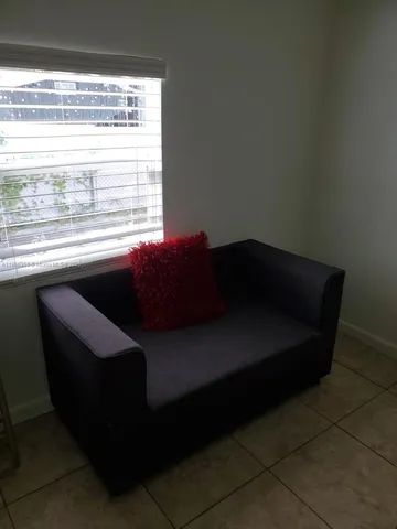 a black leather couch sitting in a living room next to a window