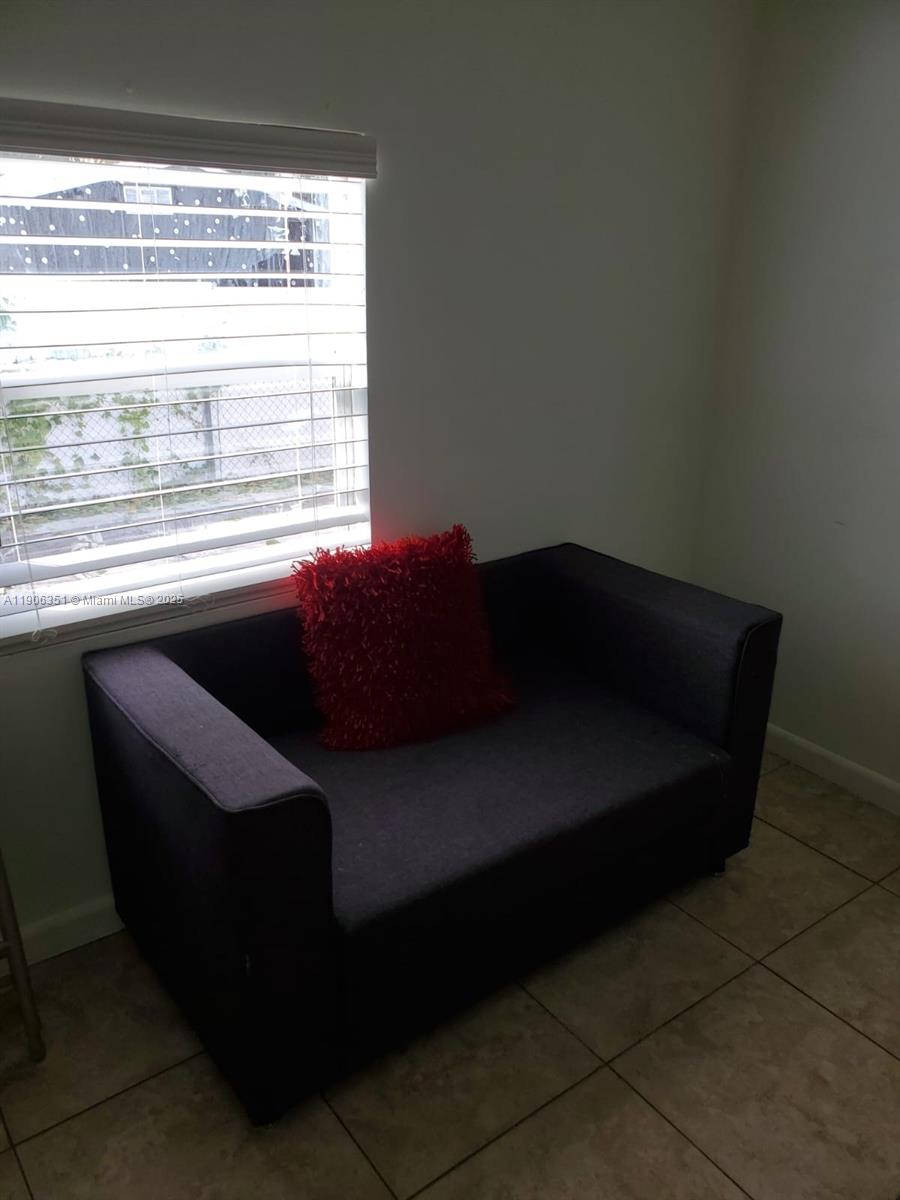 13101 Southwest 14th Street, Unit 1 Miami, FL 33184 - Photo 3 of 12 a black leather couch sitting in a living room next to a window