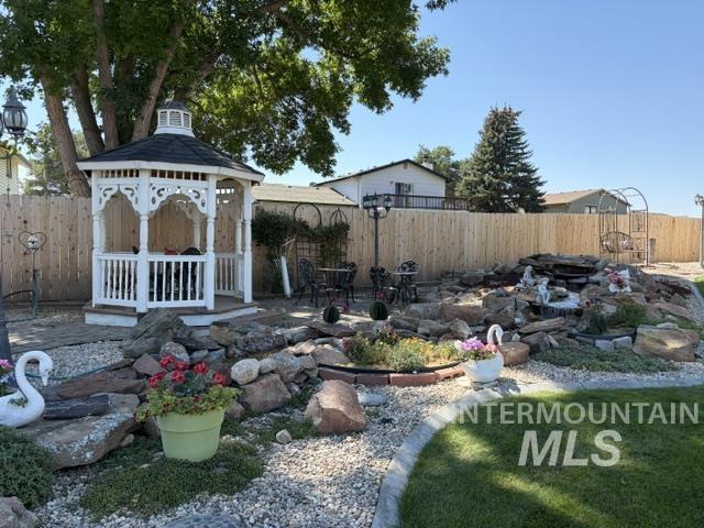 11603 West Hidden Valley Rim Road Boise, ID 83709 - Photo 3 of 4 Outdoor gazebo, rock landscaping, water feature, manicured lawn, and wood privacy fencing