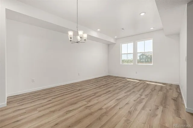 an empty room with wooden floor exposed radiator and windows