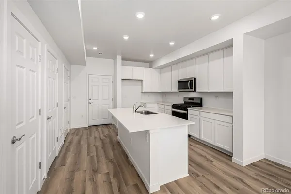 a kitchen with a sink a counter top space stainless steel appliances and cabinets