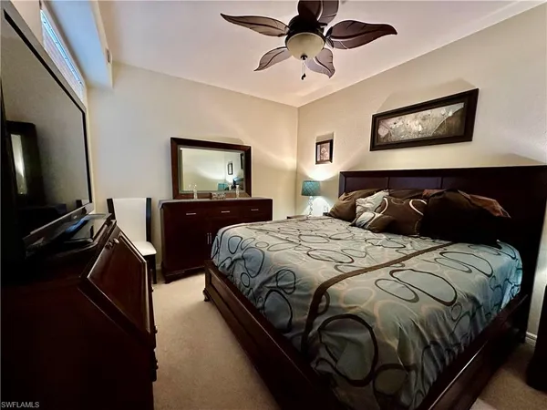 a bedroom with a bed and a flat tv screen on the dresser