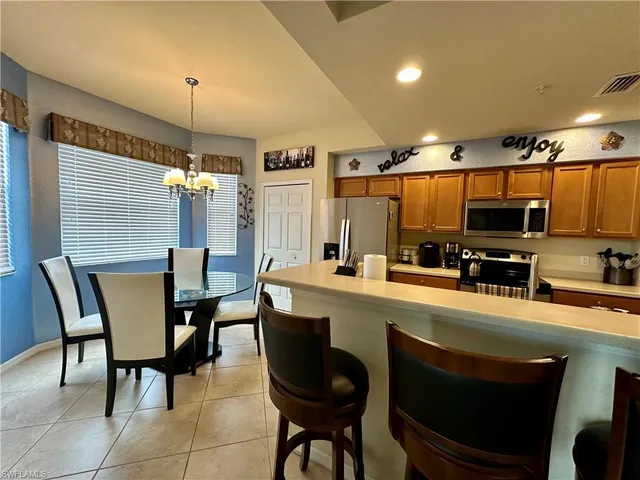 a kitchen with stainless steel appliances kitchen island granite countertop a table chairs sink and cabinets