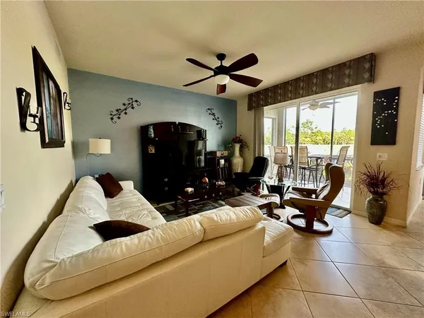 a living room with furniture ceiling fan and a large window
