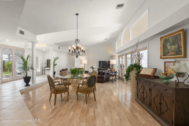 a view of a dining room and livingroom with furniture wooden floor a chandelier