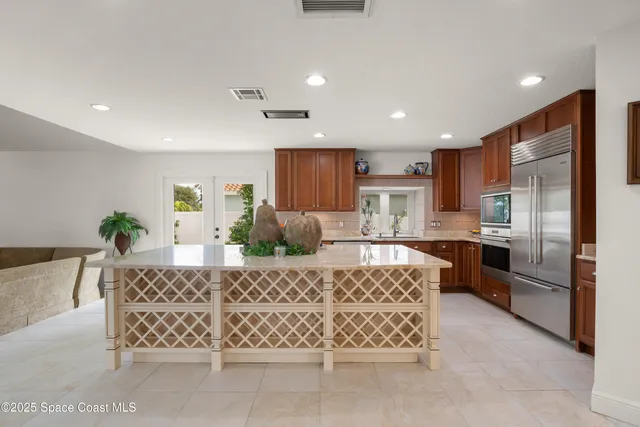 a large kitchen with kitchen island a large counter top stainless steel appliances and cabinets