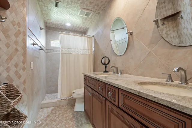 a bathroom with a granite countertop double vanity sink and mirror