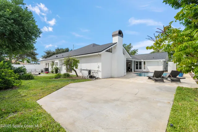 a view of a white house with a yard and potted plants