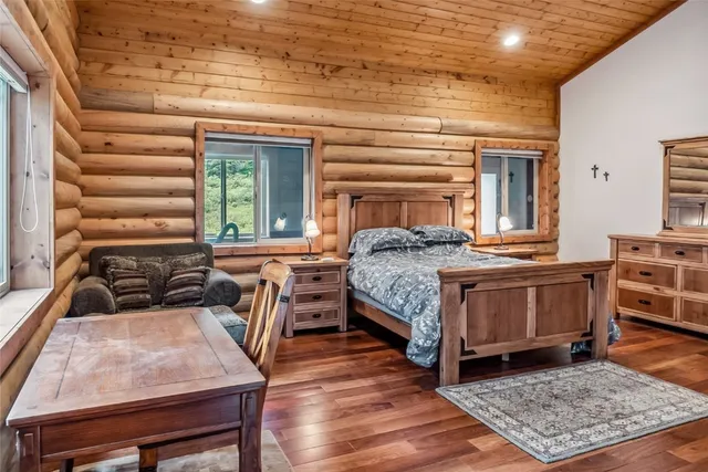 a living room with a bed and dresser with wooden floor