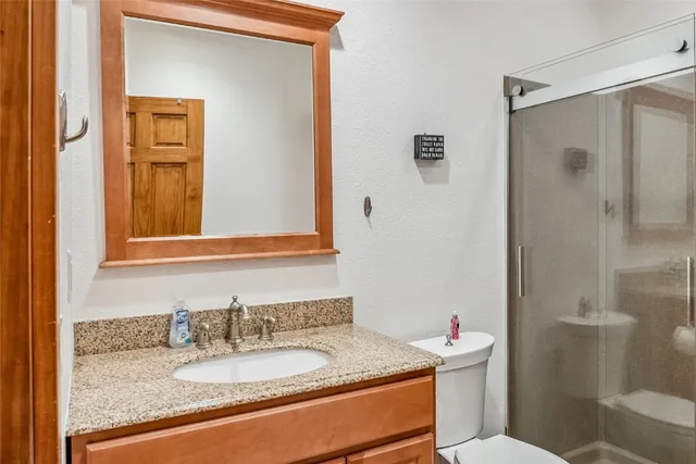 a bathroom with a granite countertop sink mirror vanity and toilet