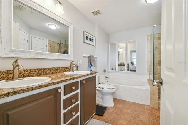 a spacious bathroom with a granite countertop sink toilet mirror and bathtub