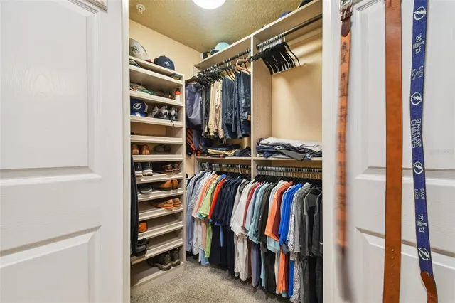 a view of walk in closet with clothes and shoes