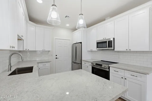 a kitchen with stainless steel appliances granite countertop a refrigerator a stove a sink a oven with a dining table and chairs