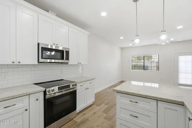 a kitchen with granite countertop white cabinets and stainless steel appliances