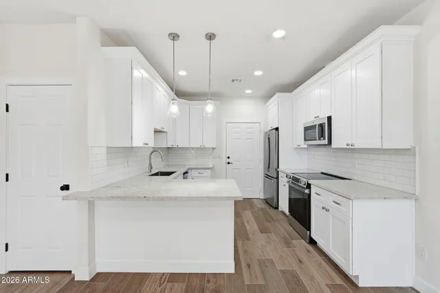 a large kitchen with stainless steel appliances kitchen island granite countertop a stove a sink a refrigerator white and white cabinets with wooden floor