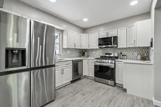 a kitchen with granite countertop a refrigerator stove and microwave