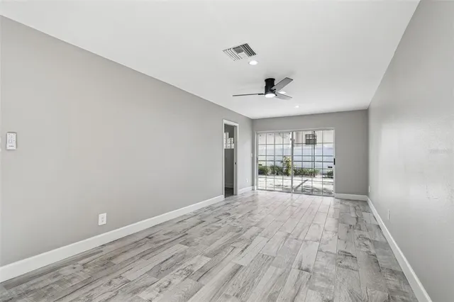 a view of empty room with wooden floor and ceiling fan