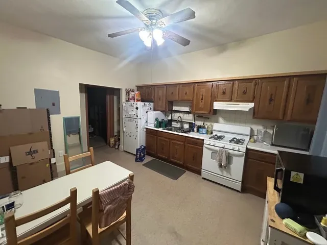 a kitchen with stainless steel appliances a stove refrigerator dining table and chairs