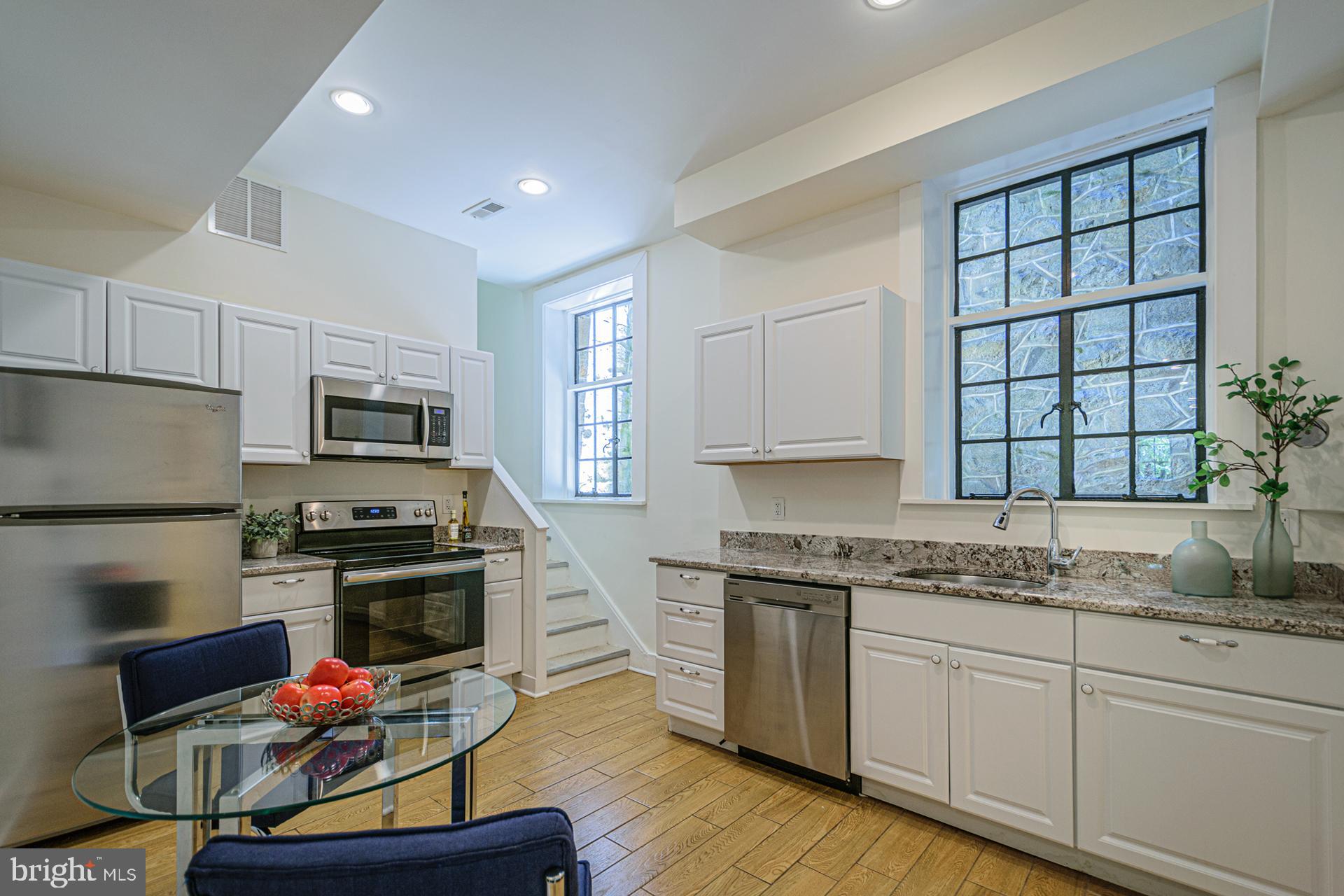 4331 Blagden Avenue Northwest Washington, DC 20011 - Photo 32 of 38 a kitchen with stainless steel appliances kitchen island granite countertop a stove a sink dishwasher and a microwave oven with wooden floor