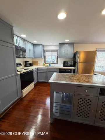 a kitchen with kitchen island granite countertop a stove a sink a refrigerator and wooden cabinets